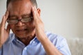 Asian old man sitting on sofa and having a headache at home. Senior healthcare concept Royalty Free Stock Photo