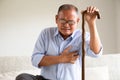 Asian old man sitting on sofa and having a with pain on heart, heart attack at home. Senior healthcare concept Royalty Free Stock Photo