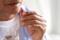Asian old man taking in pill and another hand holding a glass of clean mineral water. Senior healthcare and medicine concept Royalty Free Stock Photo