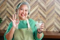 Asian old woman in good health smiling brightly holding a glass of skim milk Ready to make a thumbs up ok. Royalty Free Stock Photo