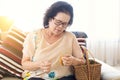 Asian old woman is knitting crochet in room