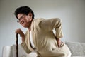 Asian old woman sitting on sofa and having a back pain, backache at home. Senior healthcare concept Royalty Free Stock Photo