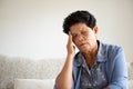Asian old woman sitting on sofa and having a headache at home. Senior healthcare concept Royalty Free Stock Photo