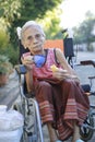 asian old woman sitting on whell chair and drinking warm beverage