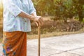 Asian old woman standing with her hands on a walking stick ,Hand of old woman holding a bamboo cane stick for helping walking Royalty Free Stock Photo