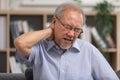 Asian Older man suffering from shoulders and neck pain sitting on sofa. Health problem retired Asian old man hands touching and Royalty Free Stock Photo