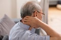 Asian Older man suffering from shoulders and neck pain sitting on sofa. Health problem retired Asian old man hands touching and Royalty Free Stock Photo