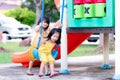 Asian older sister taught the little sister to play swings. Sisters are playing blue swing on playground near the house.