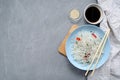 Asian oriental cuisine. Fungose glass rice noodles with vegetables, pepper and herbs in a blue plate with bamboo sticks, soy sauce