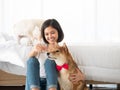Asian owner girl smile, sit and feed Japanese Shiba Inu brown short hair while white Maltese puppy playing on her bed in bedroom Royalty Free Stock Photo