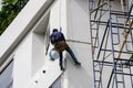 Asian Painter hanging by rope for fixing and painting exterior building wall