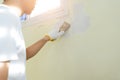 Asian painter man using scraper or spatula to remove old paint wall for cleaning, repair, preparing concrete wall before painting Royalty Free Stock Photo