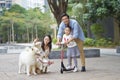 Asian parents & daughter playing scooter while walking dog in garden