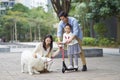 Asian parents & daughter playing scooter while walking dog in garden