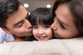 Asian Parents kissing their little daughter on both cheeks. Royalty Free Stock Photo