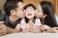 Asian Parents kissing their little daughter on both cheeks. family portrait. Royalty Free Stock Photo