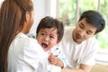 Asian Parents with mother and father trying to calm down crying infant son in living room at home Royalty Free Stock Photo