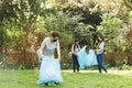 Asian parents, son and daughter in face masks putting rubbish in refuse sacks in the countryside