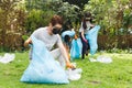 Asian parents, son and daughter in face masks putting rubbish in refuse sacks in the countryside