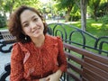 Asian park woman sitting on bench smiling happy at camera. Pretty young multiethnic woman enjoying summer in park Royalty Free Stock Photo