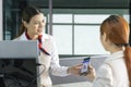 Asian passenger is showing her online check in qr code boarding pass to the airline ground crew at departure gate into the