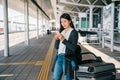 Asian passenger standing beside luggage cart