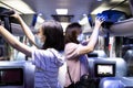 Asian passenger stowed her backpacks in a overhead storage on the tour bus,people wearing protective masks to safety from the