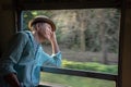 Asian passenger wearing hat looking out of train window Royalty Free Stock Photo