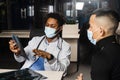 Asian patient at African doctor appointment. Fracture of the bones of foot. Black surgeon showing x-ray to patient.