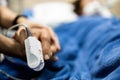 Asian patient`s hand with an attached pulse oximeter on finger for monitoring,daughter holding her mother`s hand,supporting