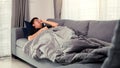 Asian people feel unhealthy while lying on the sofa at home while he have a cough due to bronchitis