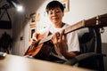 Asian people playing string music cover a song guitar sitting on chair bedroom in lighting at room