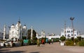 Asian people rush past the white mosque