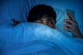 Asian people use their smartphones on the bed at night. There are some suspicions on the smartphone