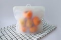 Asian persimmons stored in reusable silicone bag, to keep them fresh dish cloth with lines sits under the bag. Storing fruits