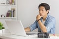 Asian Photographer or Freelancer Serious Checking Photo File in Laptop in Home Office