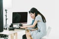 Asian Photographer and model sitting at the table and looking pictures from screen of desktop computer with white background Royalty Free Stock Photo