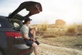 Asian photographer sitting at edge of trunk looking at view