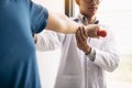 Asian physiotherapist helping a patient lifting dumbbells work through his recovery with weights in clinic room Royalty Free Stock Photo