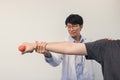 Asian physiotherapists help raise arms for patients to raise dumbbells through his rehabilitation in the clinic