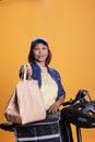 Asian pizzeria worker holding recycled paper bag delivering take away food to client