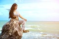 Asian plus size fat and overweight woman in a white dresses sitting on rock on the beach. Royalty Free Stock Photo