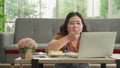 Asian plus size woman in casual eating working online with laptop computer online at home, eating unhygienic food