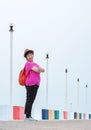 Asian plus size woman smiling and looking at camera while posing on multicolor bridge at sea viewpoint after raining Royalty Free Stock Photo