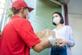 Asian postman, deliveryman wearing mask carry small box deliver to customer in front of door at home. Man wearing mask prevent cov Royalty Free Stock Photo