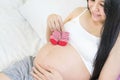 Asian pregnant Happy Woman holding red baby shoes in her Hands. Mom Expecting Baby. Pregnant Woman Belly. Pregnancy. Baby Shower Royalty Free Stock Photo