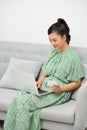 Asian pregnant mother ordering clothes for her baby, using laptop computer and credit card at home Royalty Free Stock Photo