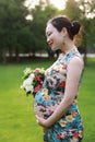 Asian pregnant woman in Chinese traditional cheongsam chi-pao hold bouquet in garden forest lawn outdoor nature free relax happy Royalty Free Stock Photo