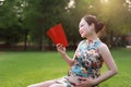 Asian pregnant woman in Chinese traditional cheongsam chi-pao read book in garden forest lawn outdoor nature free relax happy Royalty Free Stock Photo