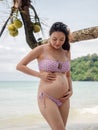 Asian pregnant woman posture on tropical sand beach with palm tree in sunny day in Thailand. Pregnancy relaxation from depression Royalty Free Stock Photo